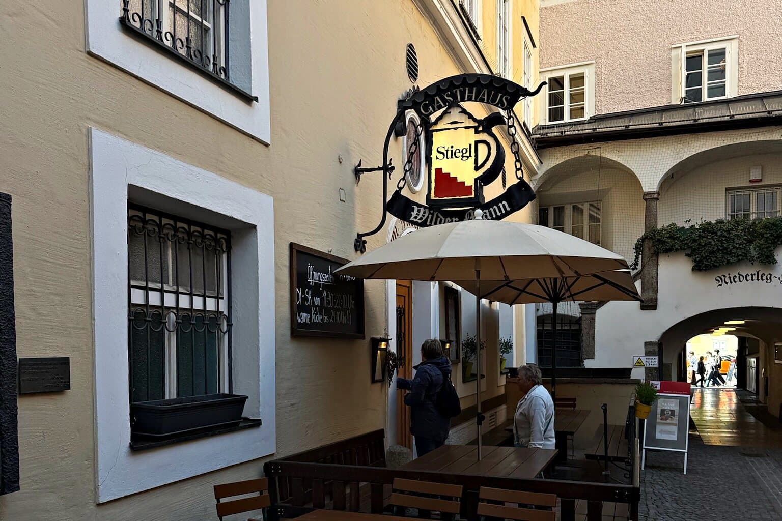 Gastgarten und Wirtshausschild von Zum Wilden Mann im Durchhaus an der Getreidegasse, Salzburg